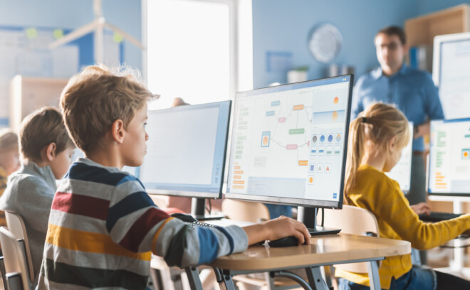 Elever sitter i klasserommet med pc-skjerm foran seg