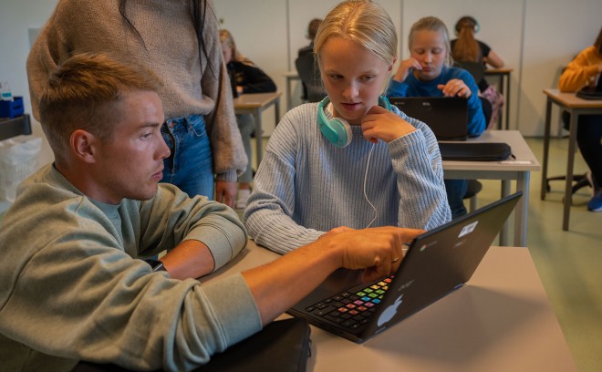 Lærer peker på en pc-skjerm mens elev følger med